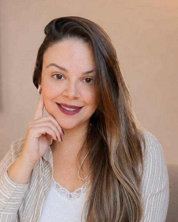 Retrato de Patrícia Moreira sorrindo, com a mão apoiada no rosto.